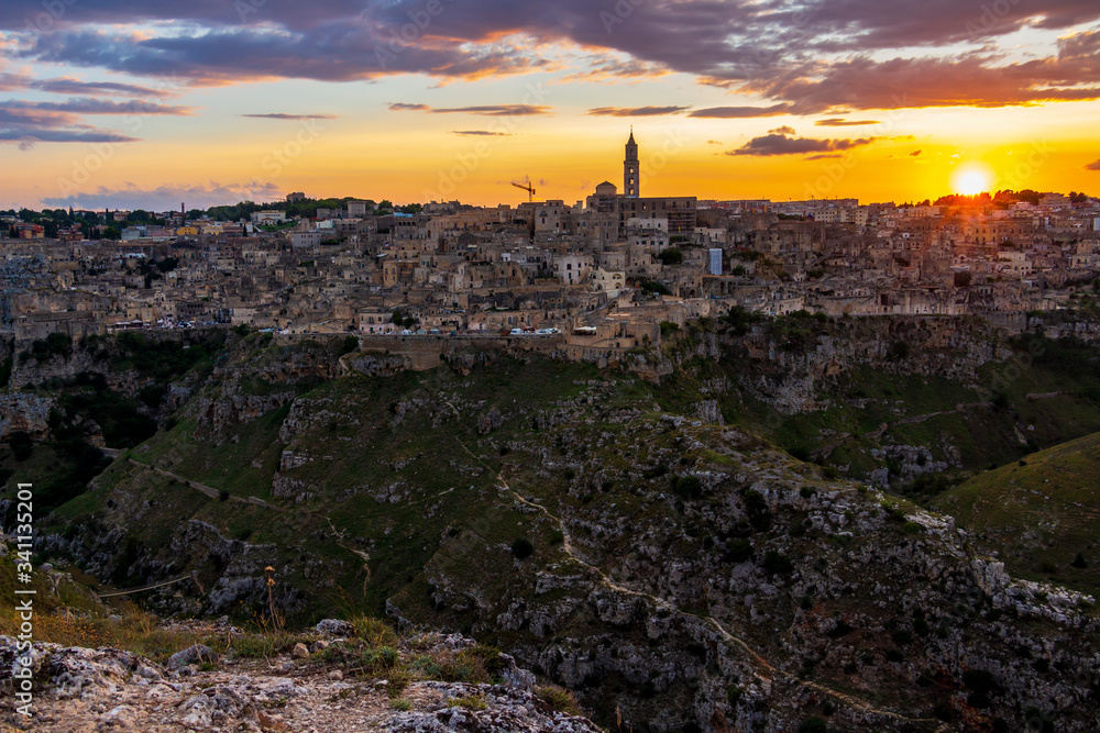 Amazing distant sunset panoramic view of Matera from Parco della Murgia Materana or Park of the Rupestrian Churches of Matera in the Province of Matera, Basilicata Region, Italy