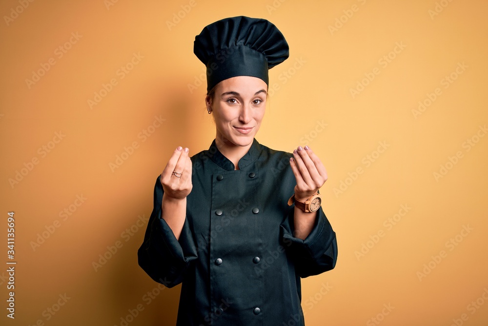 Young beautiful chef woman wearing cooker uniform and hat standing over yellow background doing money gesture with hands, asking for salary payment, millionaire business Young beautiful chef woman wearing cooker uniform and hat standing over yellow background doing money gesture with hands, asking for salary payment, millionaire business