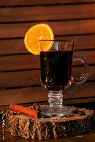 Mulled wine in a glass with an orange, wood backgroud