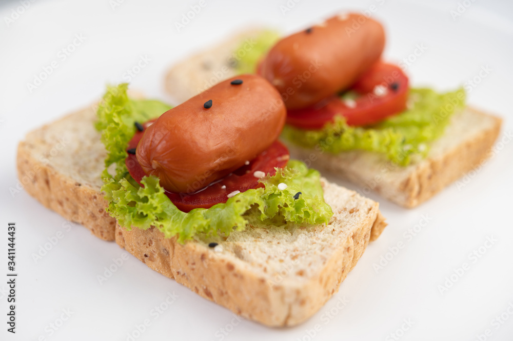 Sausage with tomatoes, salad and two sets of bread on a white plate. Sausage with tomatoes, salad and two sets of bread on a white plate.