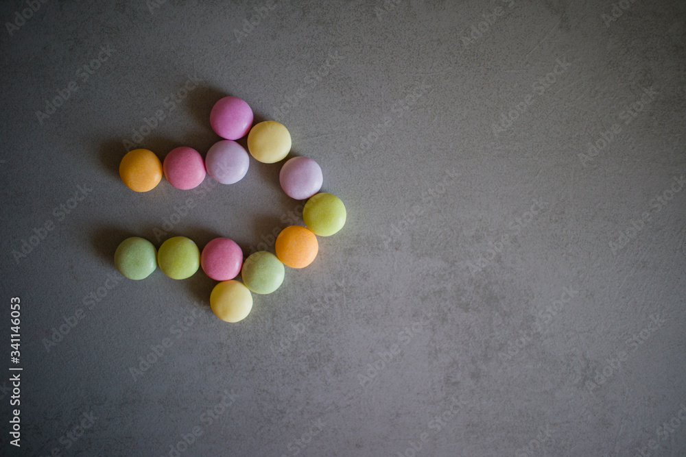 arrow of colorful candies on a gray table arrow of colorful candies on a gray table