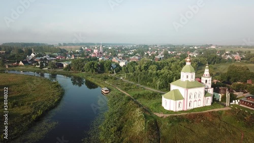 4K aerial dense sunny summer morning video of Suzdal churches, buildings, hills, fields and cathedrals located on Kamenka River shore in Vladimir Region, Russia