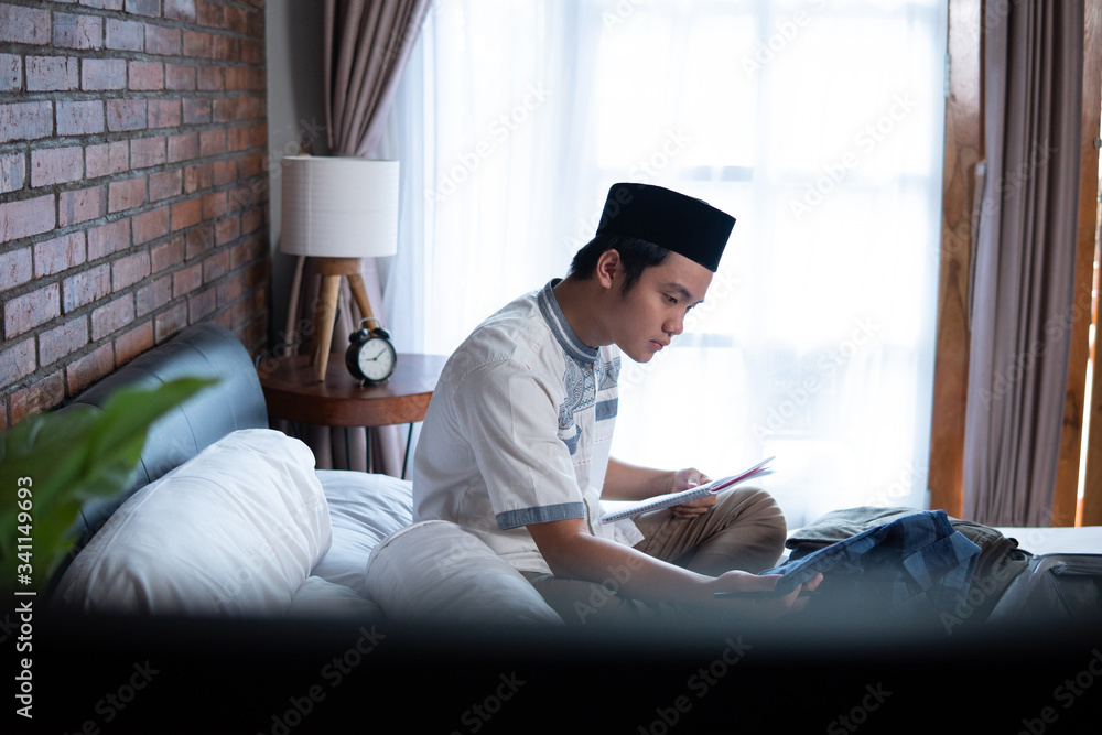 Muslim asian male holding paper checklist for luggage before go travelling