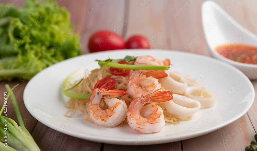 Stir-fried instant noodle with prawn and crab stick along in a white dish. Stir-fried instant noodle with prawn and crab stick along in a white dish.
