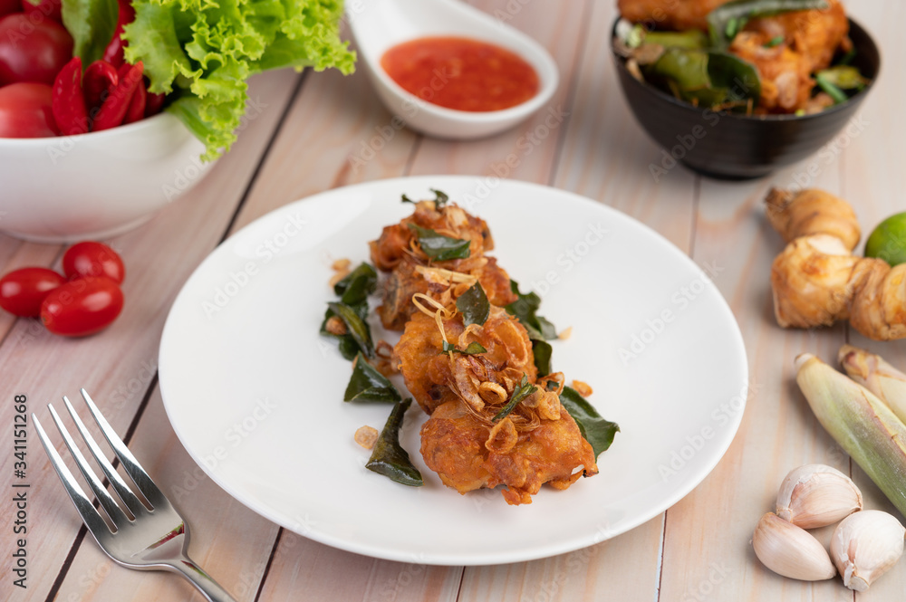 Herb fried chicken on a white plate on a wooden floor. Herb fried chicken on a white plate on a wooden floor.