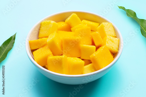 Mango cube slices in white bowl on blue background.