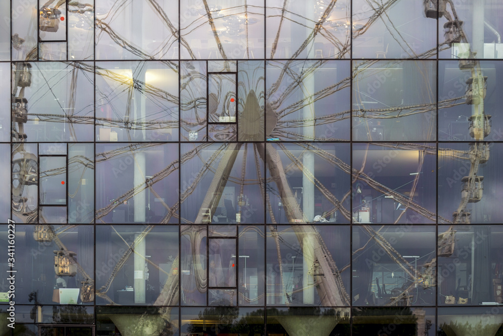 Reflet d'une grande roue dans un immeuble vitré