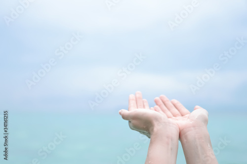 Woman hands place together like praying in front of nature clean beach and blue sky. © ant