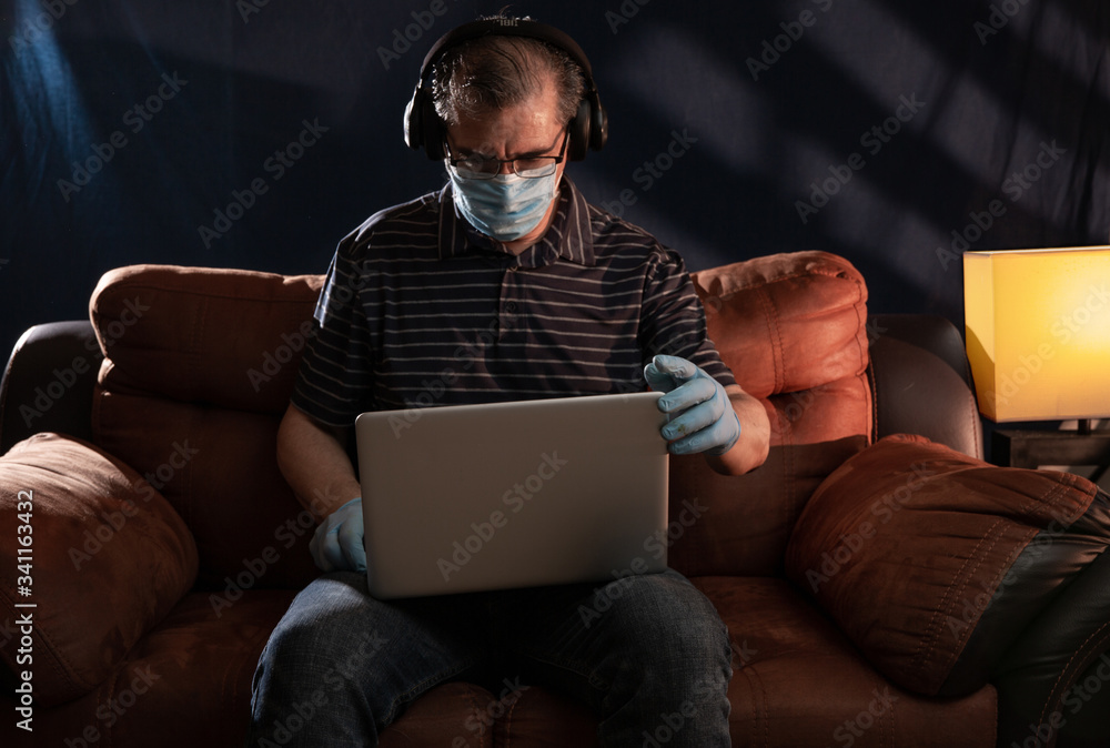 Middle aged man working at home on his computer for the coronavirus using protective equipment such as gloves and mask Middle aged man working at home on his computer for the coronavirus using protective equipment such as gloves and mask