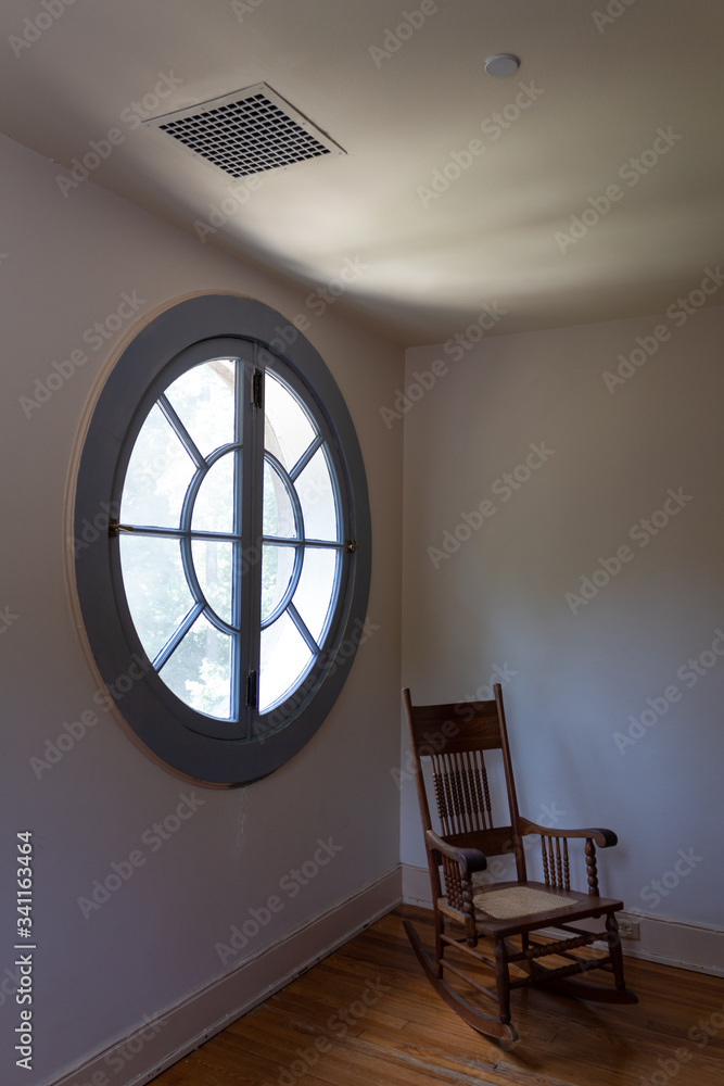 Large circular round window seen from interior, empty rocking chair