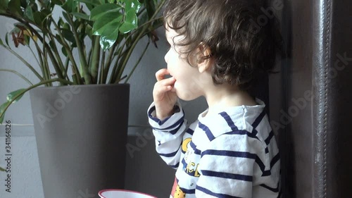 Cute little boy eating snack and watching tv while sitting on the potty
