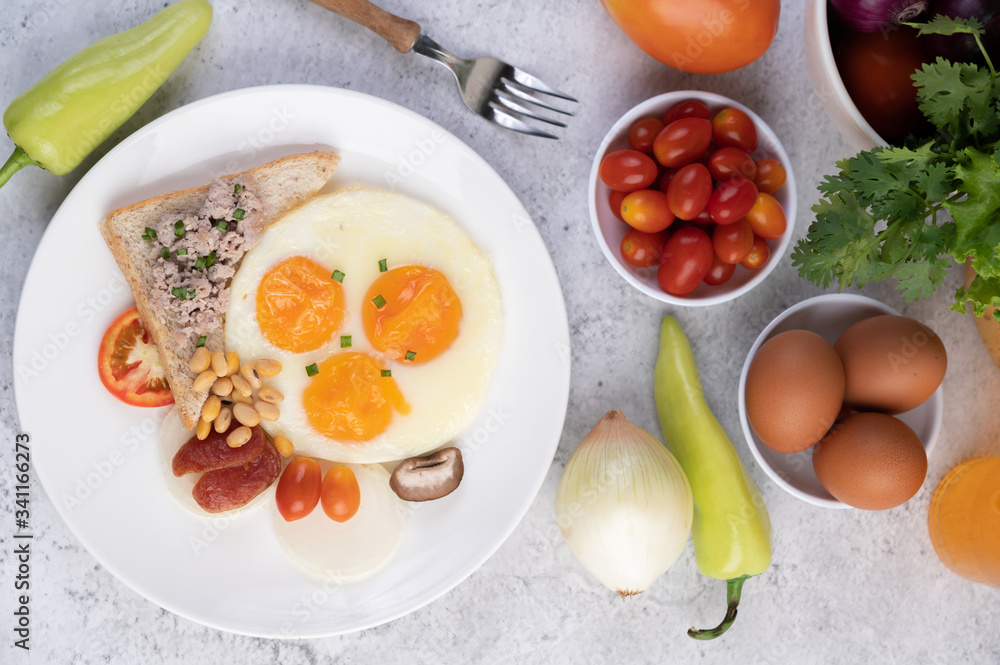 Breakfast consists of fried eggs, sausage, minced pork, bread, red beans and soy on a white plate. Breakfast consists of fried eggs, sausage, minced pork, bread, red beans and soy on a white plate.