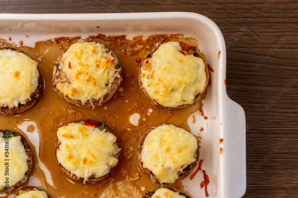 Baked stuffed mushrooms in a baking dish on a wooden table, top view Baked stuffed mushrooms in a baking dish on a wooden table, top view