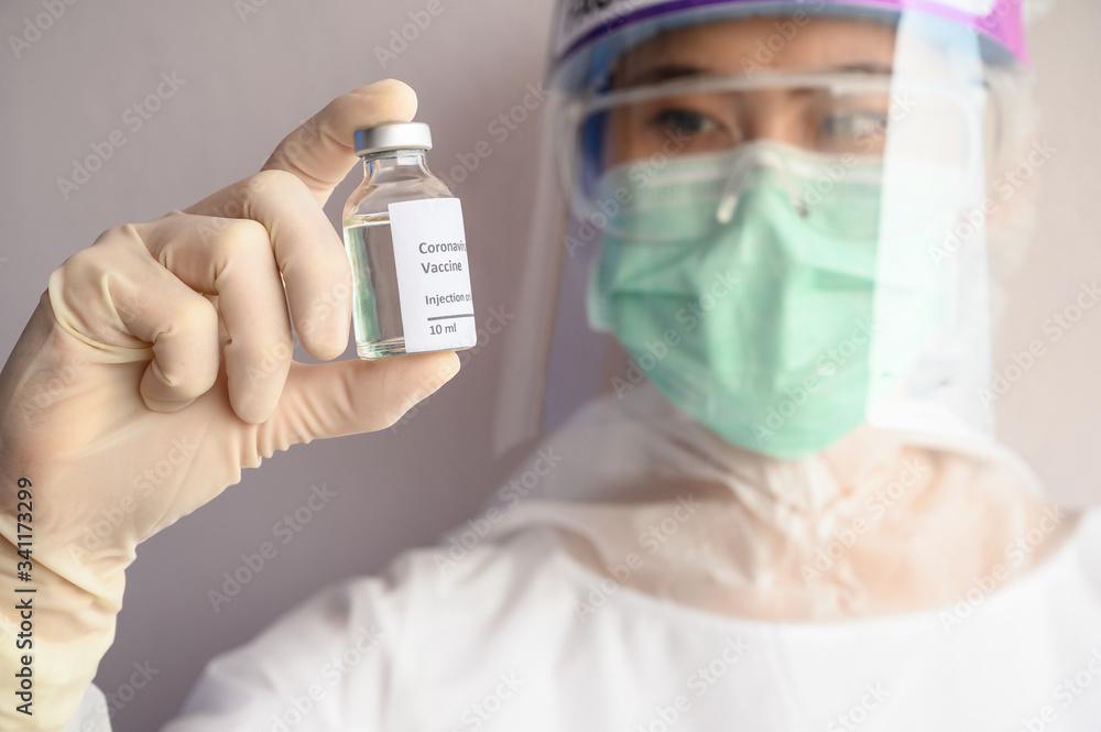 Fototapeta premium Scientist doctor holding a sample test bottle of Covid-19 vaccine. Vaccination is one of the most effective ways to prevent diseases and helps the body’s immune system from virus.