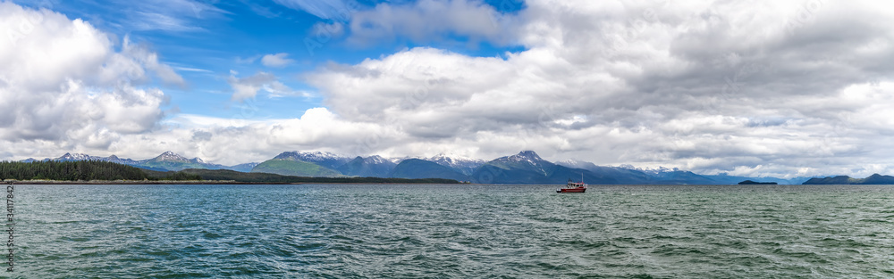 Beautiful panorama with a tiny fishing boat sailing and mountains, clouds and blue sky in the background in Alaska, USA Beautiful panorama with a tiny fishing boat sailing and mountains, clouds and blue sky in the background in Alaska, USA