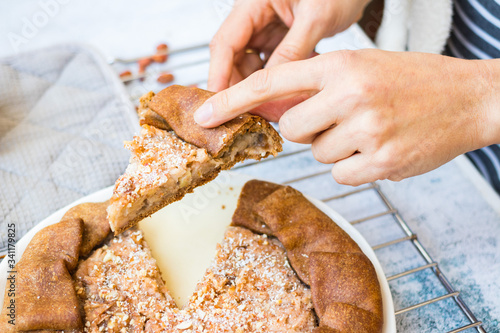 Woman cut a piece of baked apple, nuts tart, pie or cake. Vegan sweet dessert on plate. 