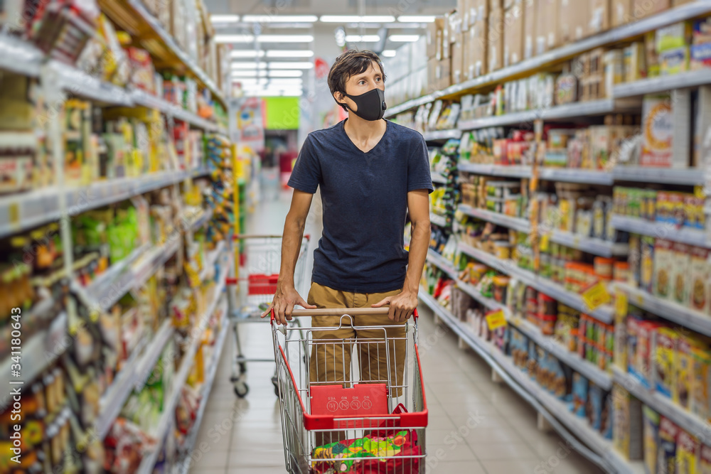 Alarmed man wears medical mask against coronavirus while grocery shopping in supermarket or store- health, safety and pandemic concept - young woman wearing protective mask and stockpiling food