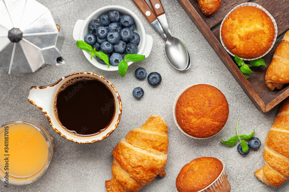 Continental breakfast captured from above (top view, flat lay). Coffee, juice, croissants,muffins and blueberry. Continental breakfast captured from above (top view, flat lay). Coffee, juice, croissants,muffins and blueberry.