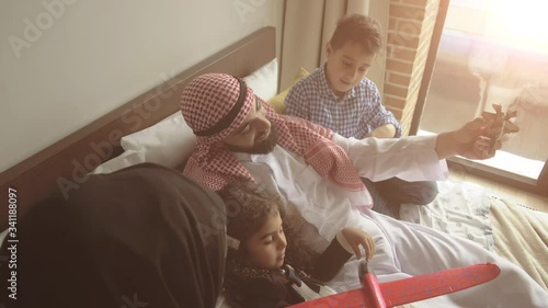 Middle eastern family at home on couch. Father playing with his kids.
