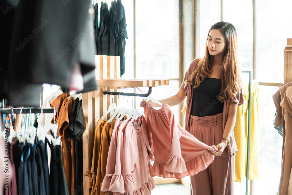 beautiful asian shopping woman looking at some clothes in the store