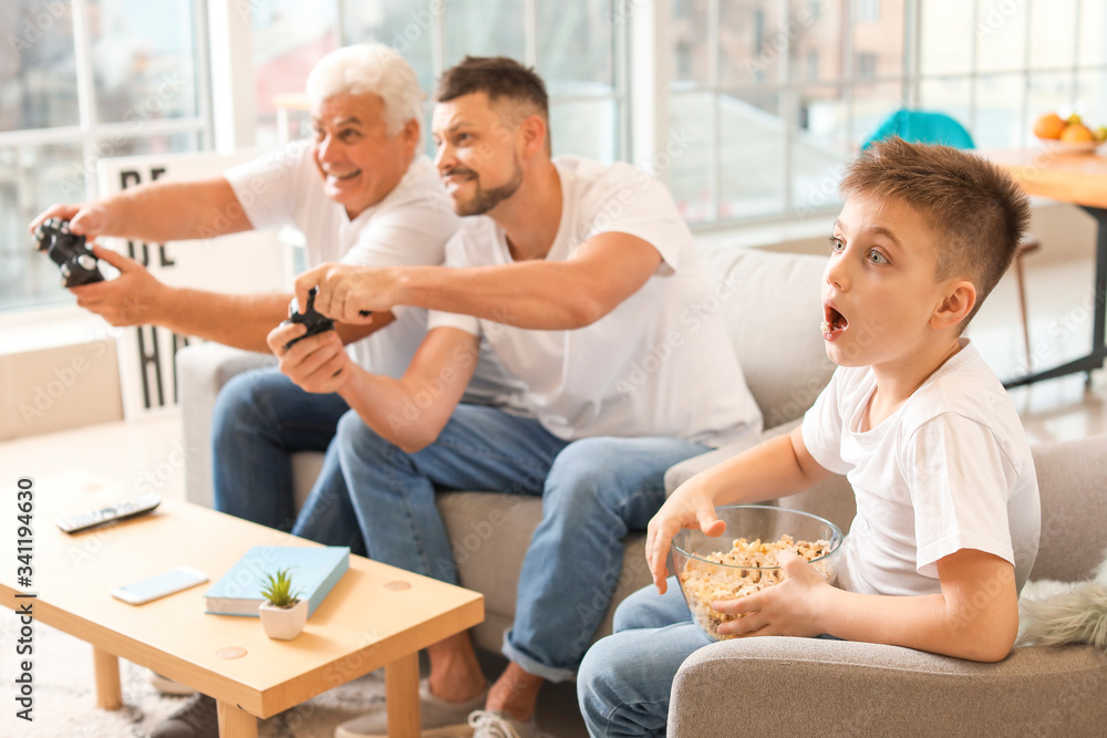 Man with his father and son playing video games at home Man with his father and son playing video games at home