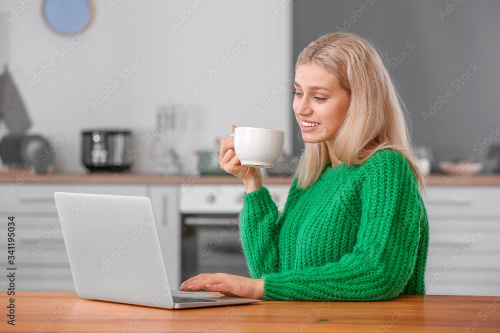 Beautiful young woman with laptop drinking tea at home Beautiful young woman with laptop drinking tea at home