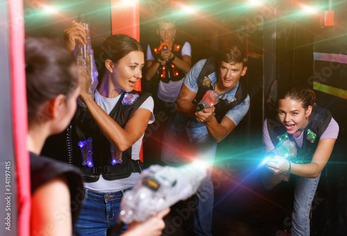 Portrait of happy young friends playing laser tag game with la