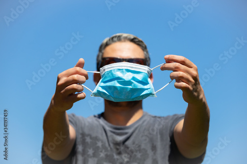 A man puts on his surgical mask, selective focus on mask. PPE against covid19.