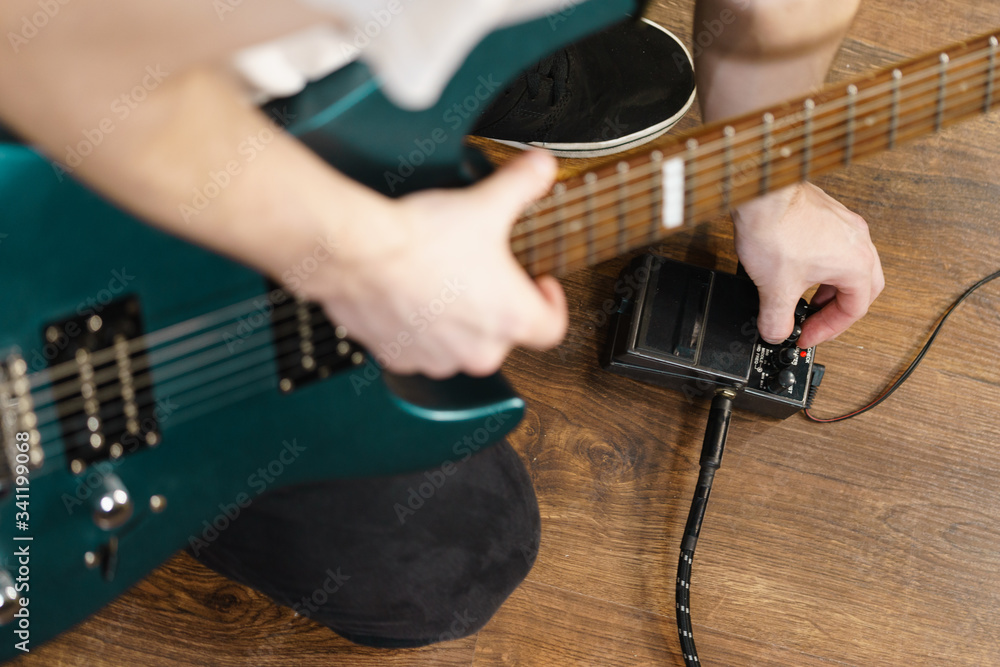Naklejka premium Man adjusting guitar effects pedal