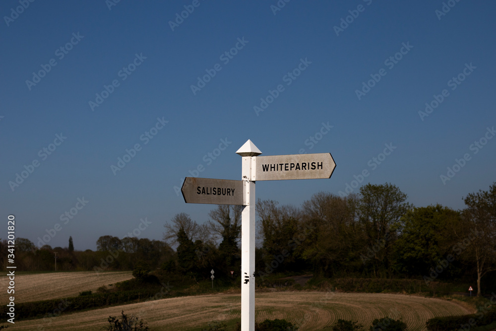 Salisbury & Whiteparish direction sign at rural road junction set against a late spring evening clear blue sky
