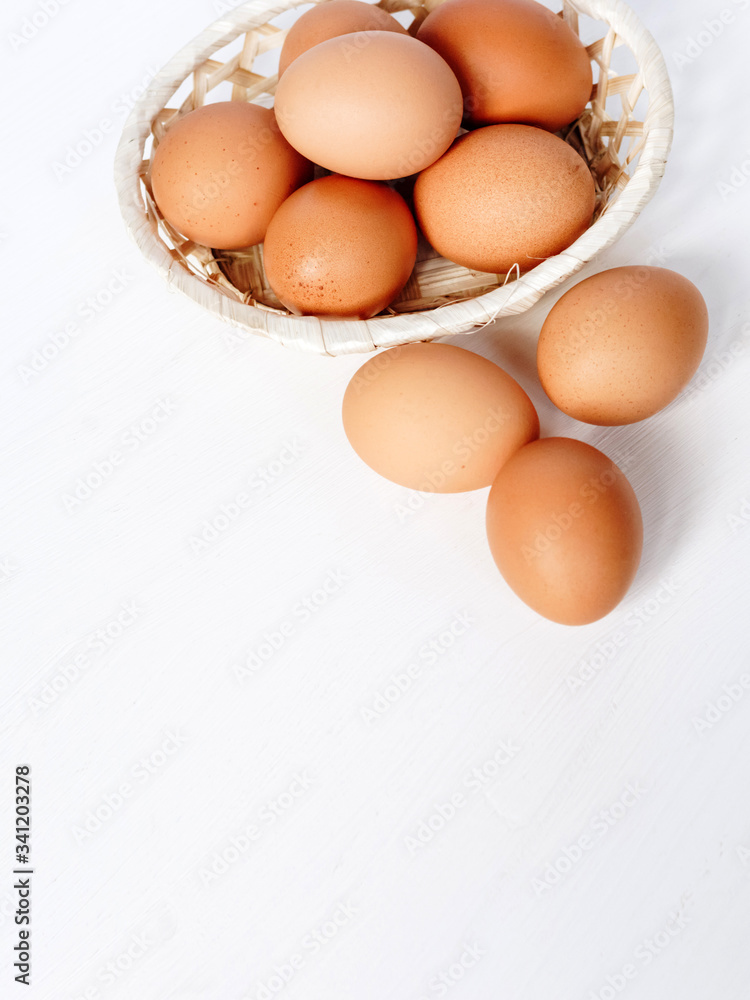 Brown chicken eggs in a straw basket on white wooden background. Top view with copy space. Brown chicken eggs in a straw basket on white wooden background. Top view with copy space.