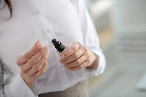 Woman in a white shirt holding a sanitizer