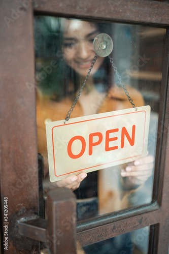 Leinwand Poster young woman business owner turn the open sign when open the shop