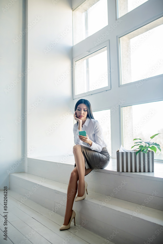 Long-haired woman in a white blouse looking sad reading messages Long-haired woman in a white blouse looking sad reading messages