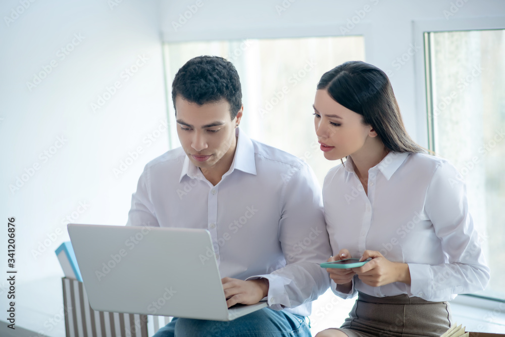 Two colleagues sitting near the window and looking involved
