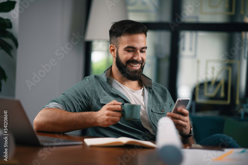 Young businessman drinking coffee in office. Handsome man at work.	