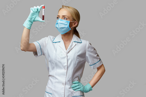 medical doctor nurse woman wearing protective mask and gloves - holding virus blood test
