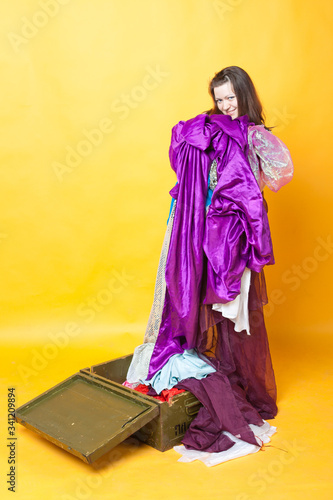 young brumette lass puts away a lot of things in a wooden box, on a bright yellow background photo