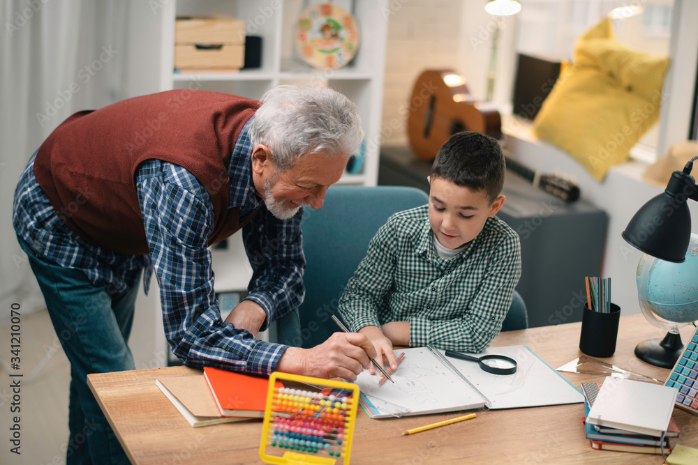 Grandfather and grandson working homework together. Grandpa and grandson enjoying at home. Grandfather and grandson working homework together. Grandpa and grandson enjoying at home.