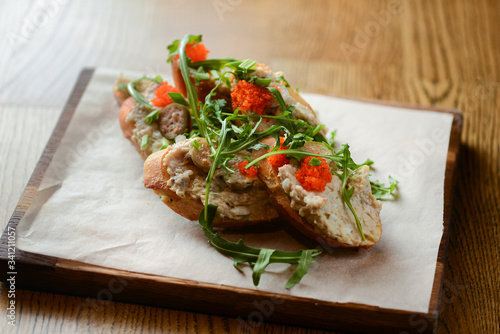 Italian bruschetta with salmon butter, capelin caviar, cherry tomatoes and parsley served on wooden cutting board