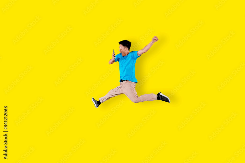 Happy young man jumping with cellphone