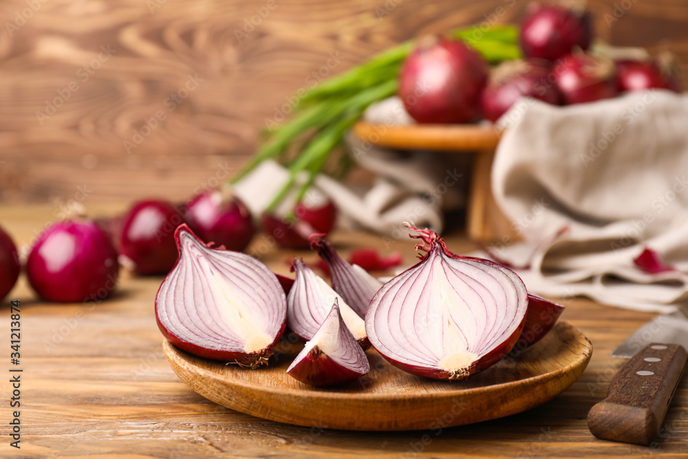 Plate with pieces of fresh raw onion on wooden background