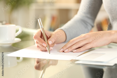 Woman hands writing a letter on a desk at home photo