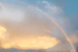 Rainbow against a background of clear, blue sky and golden clouds. Copy Space