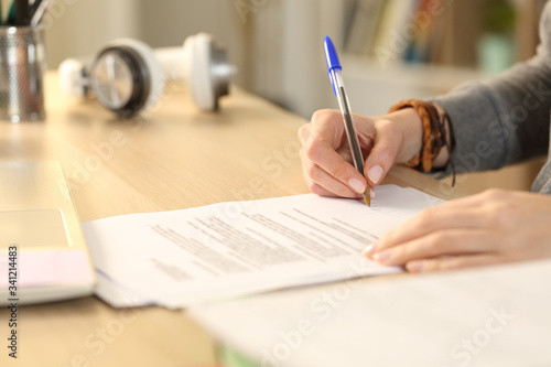 Student girl hands signing contract at home