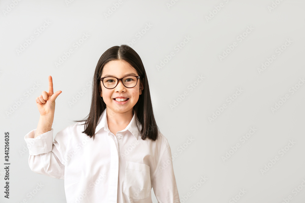 Cute little businesswoman with raised index finger on grey background Cute little businesswoman with raised index finger on grey background
