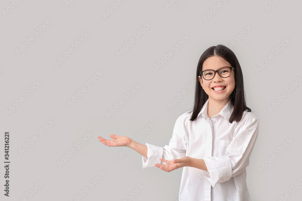 Cute little businesswoman showing something on grey background Cute little businesswoman showing something on grey background