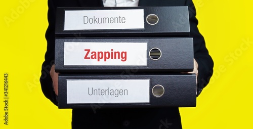 Zapping – Finanzen/Wirtschaft. Mann trägt einen Stapel Aktenordner. Ein Ordner hat die Beschriftung Zapping. Symbol für Business, Statistik photo