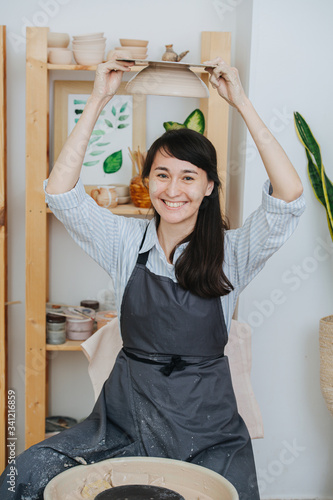Woman joking around, holding pottery wheel upside down above her head