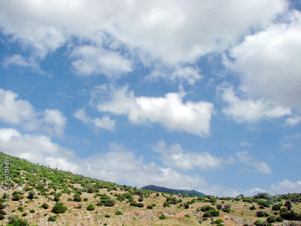 Panorama of green hills in the outskirts of Florence on a background of blue barely cloudy sky.